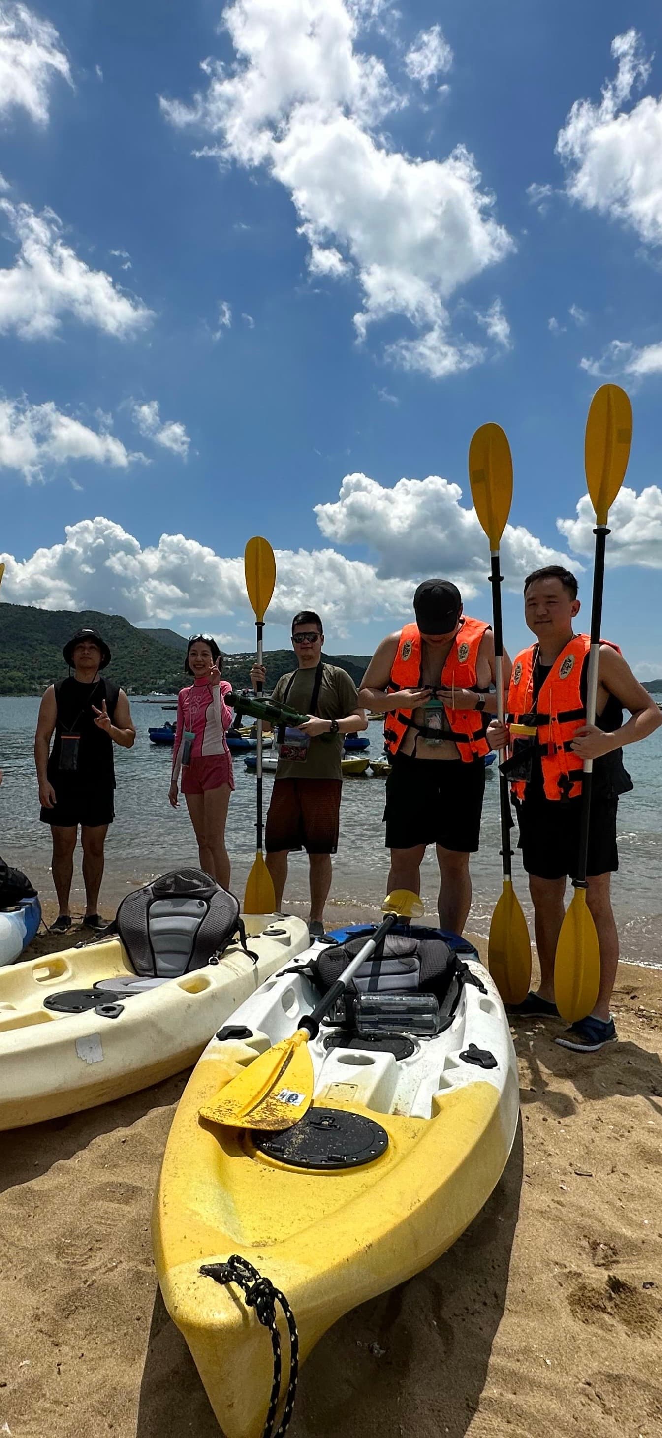 Kayaking group with paddles raised on a Hong Kong beach