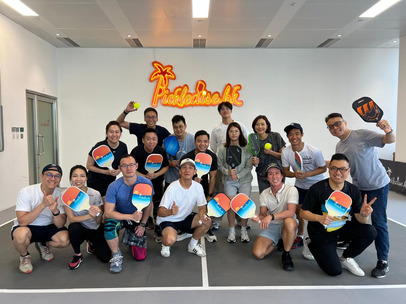 Pickleball crew posing with paddles at a Hong Kong indoor court